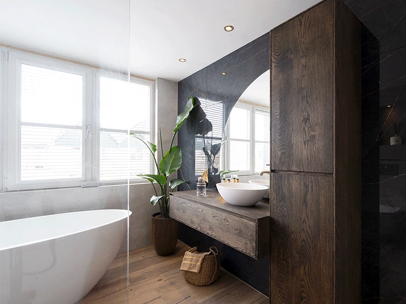 Badkamer met donker houten meubels en een vrijstaand bad bij het raam