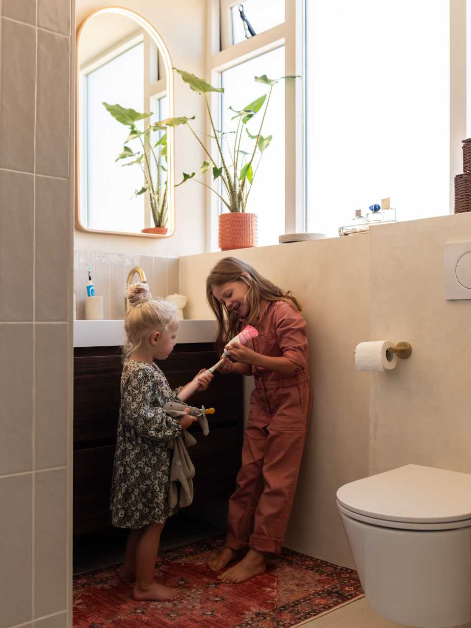 Kinderen van familie Mussche in hun lichte badkamer met messing details